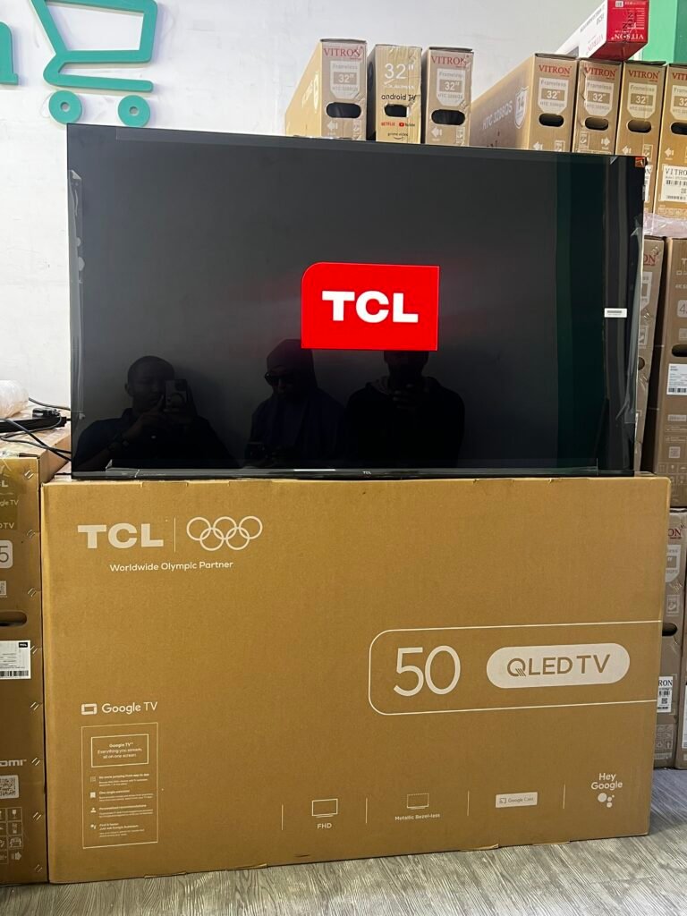 Large TCL 50-inch QLED TV in a boxed display at a store, with other boxes and a cardboard box beneath reading 'Worldwide Olympic Partner'