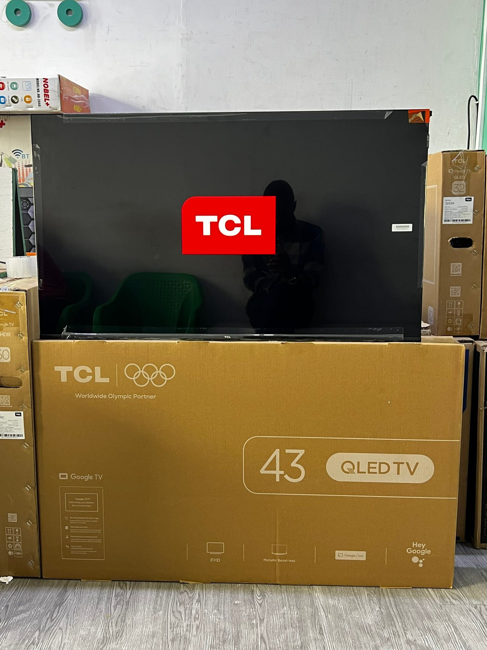 TCL 43-inch QLED TV on display, surrounded by boxed packaging in a store setting.