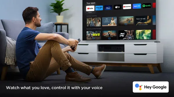 image – TCL East Africa Kenya Man sitting on the floor watching a TV with streaming apps; voice control with Hey Google.